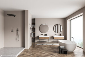 Beigefarbenes Panorama-Badezimmer mit Duschkabine, trendigen, runden Spiegeln mit zwei Waschtischen, einer ovalen, weißen Keramikbadewanne und Parkettboden.