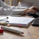 Rotstift und Brille auf einem Schreibtisch bei der Textkorrektur