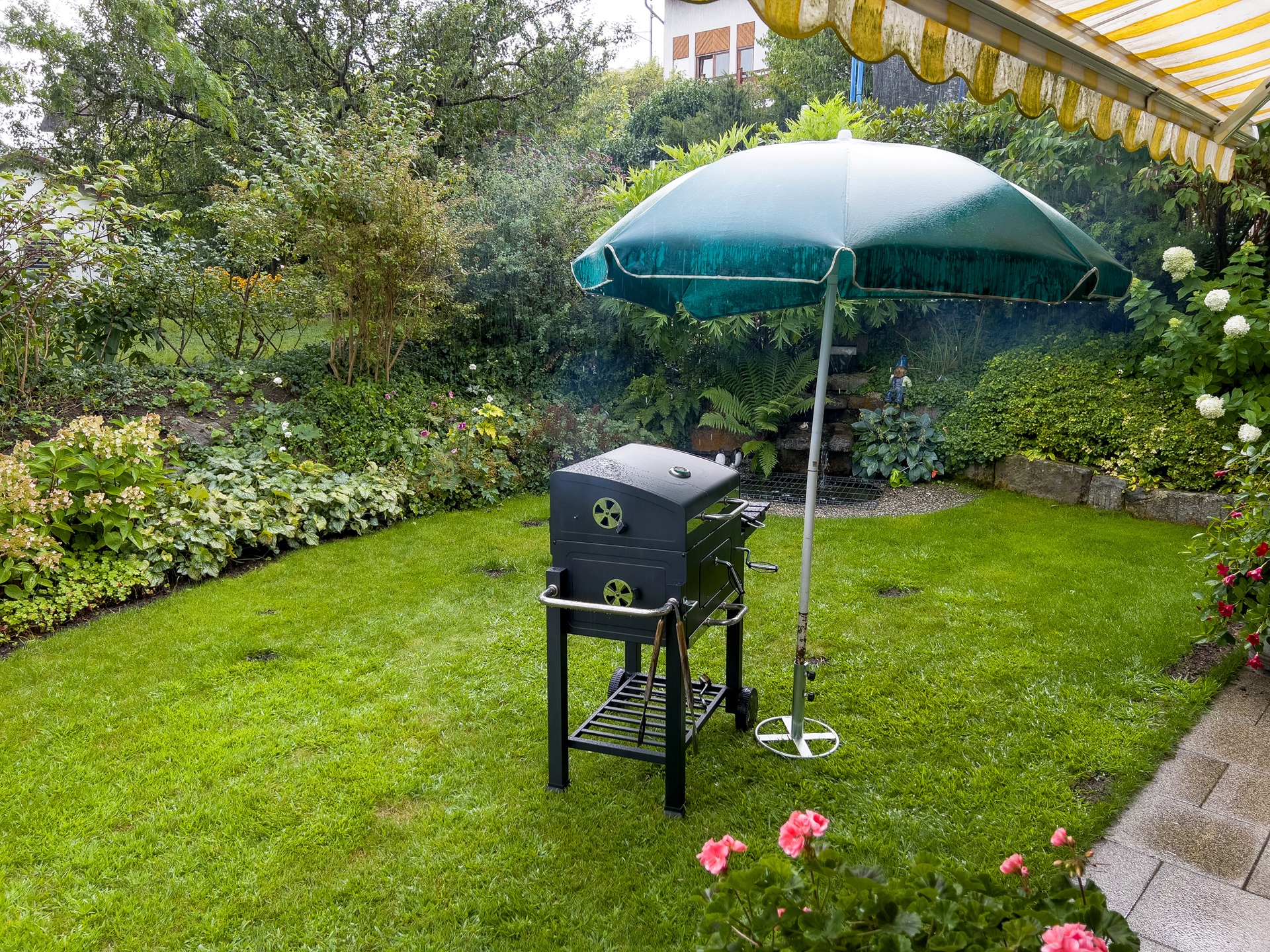 Grill mit Sonnenschirm als Regenschutz im Garten | mobile Heizgeräte