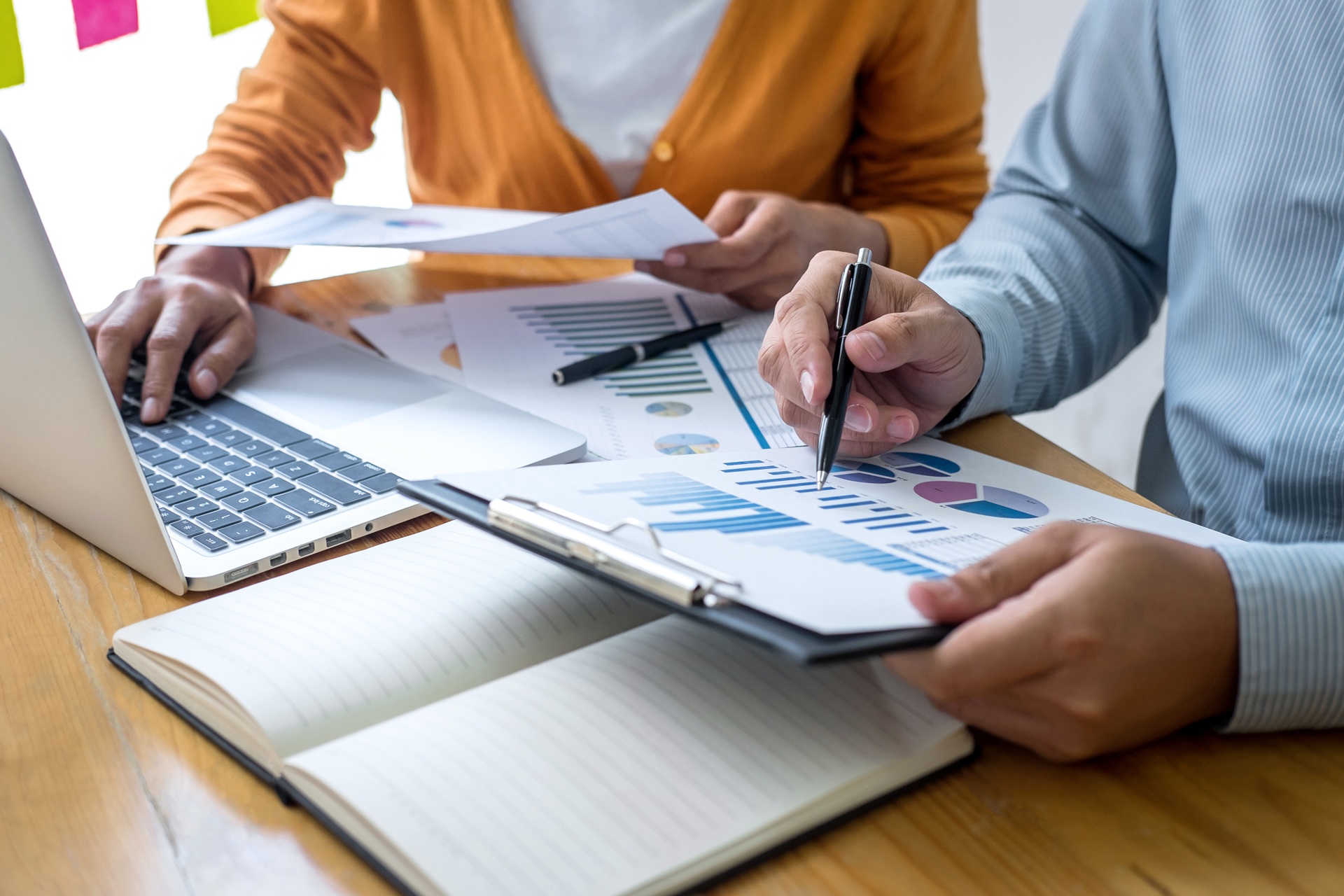 Zwei Personen analysieren Charts und Berichte am Tisch | Marketingübersetzung